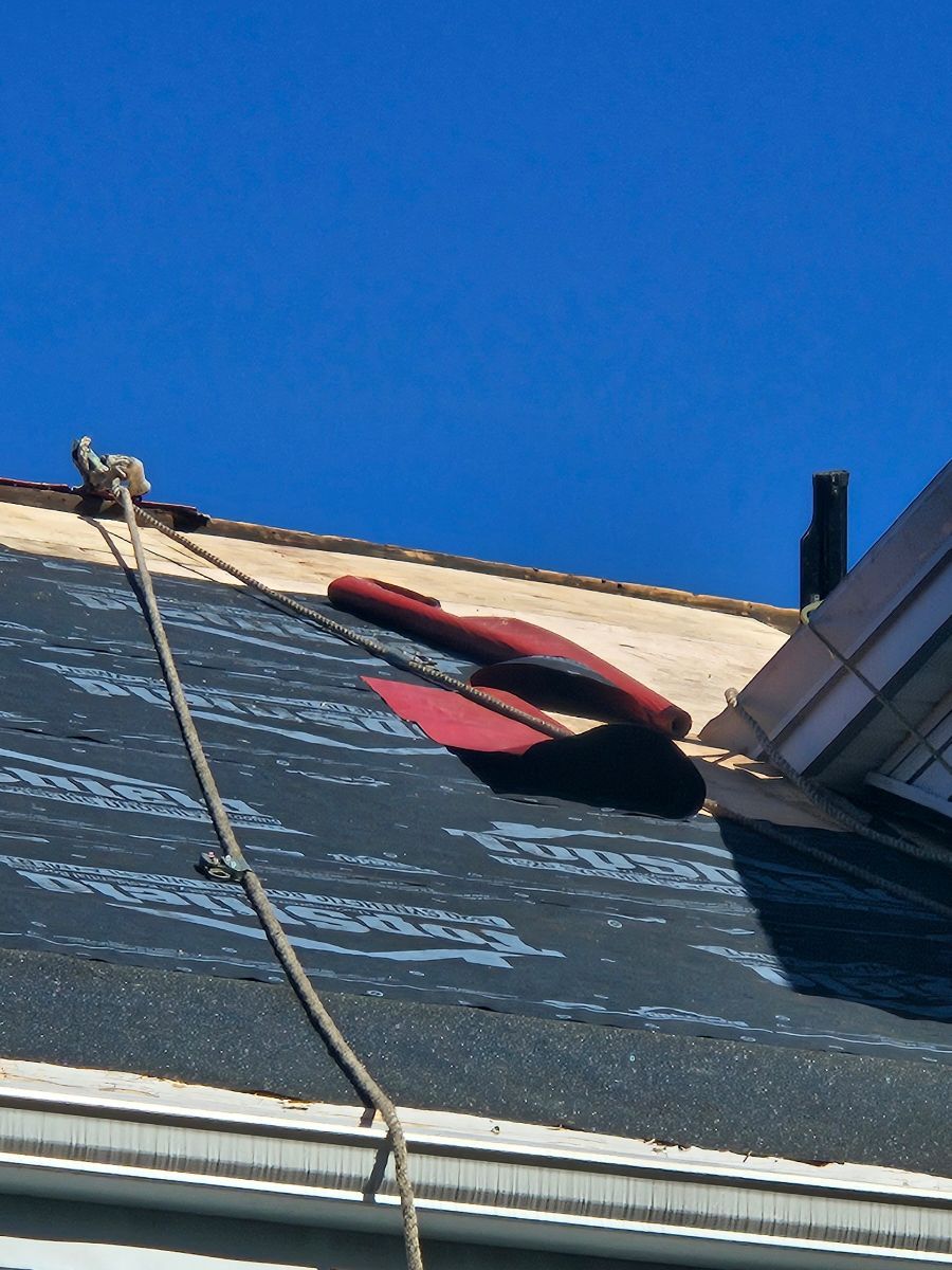 A roof with a rope attached to it and a blue sky in the background