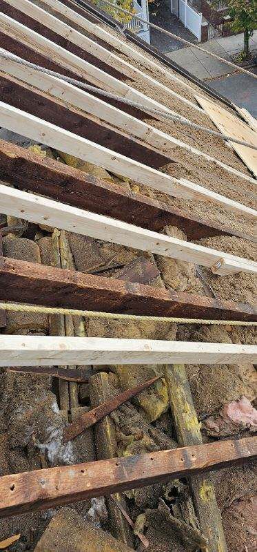 A close up of a roof with wooden beams and bricks.