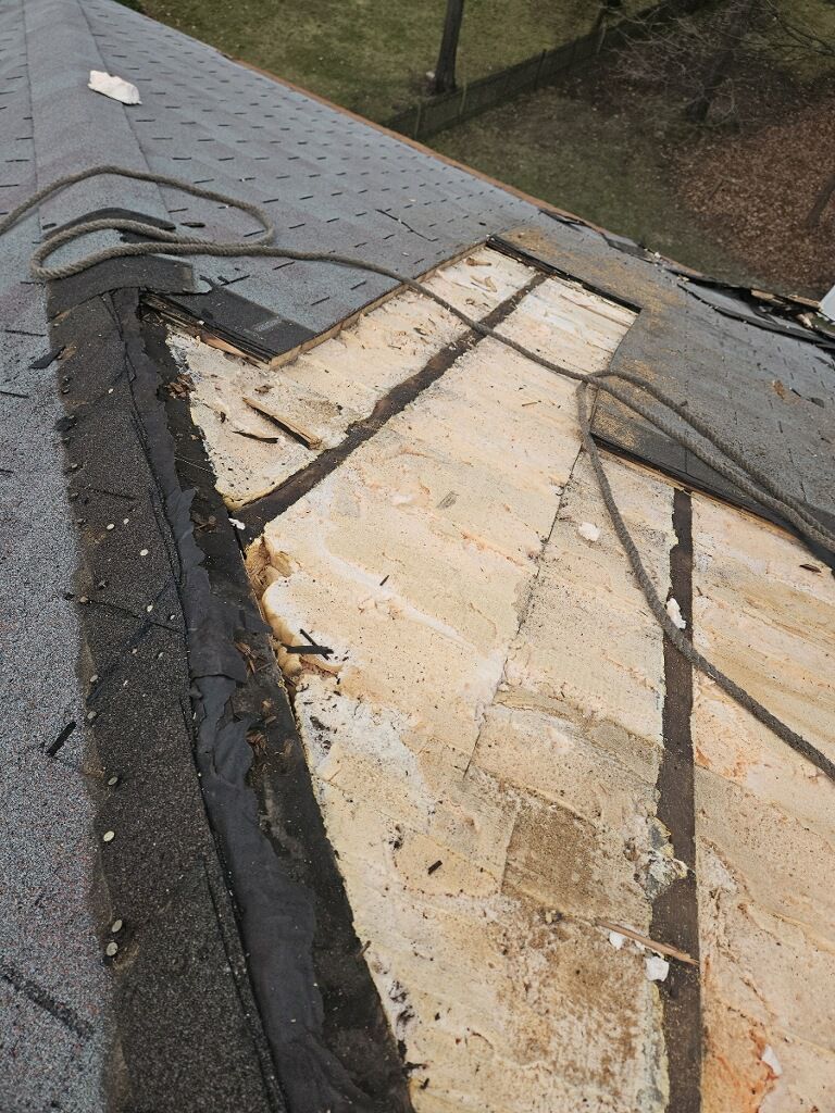 A close up of a roof with a piece of shingles missing.