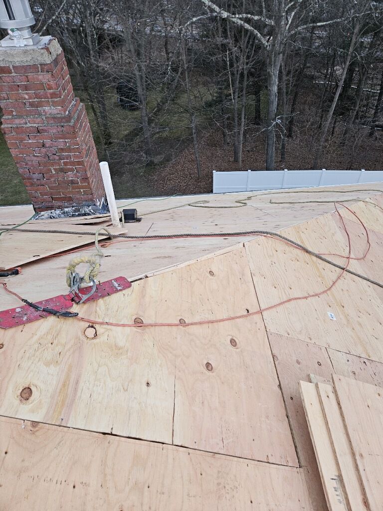 A roof is being built with plywood and a brick chimney.