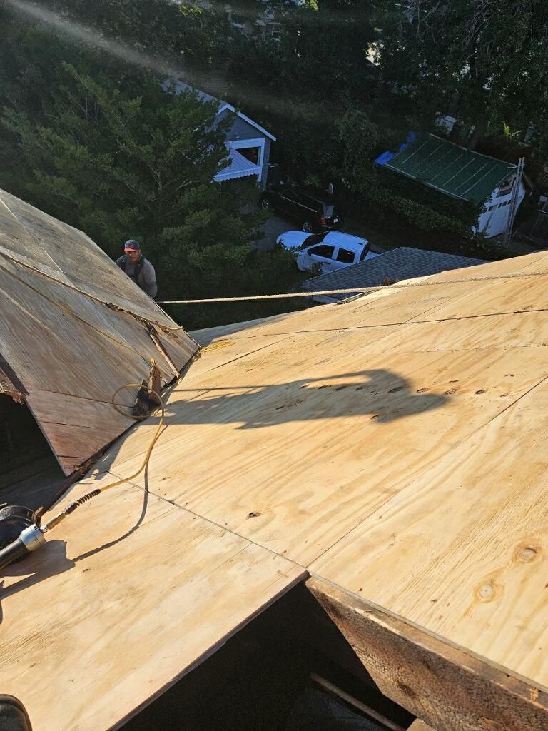 A man is standing on top of a wooden roof.