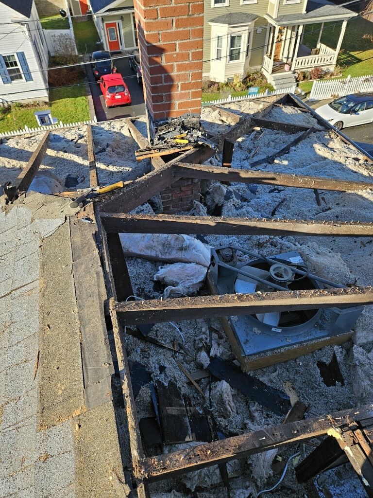 A brick chimney is being removed from the roof of a building.