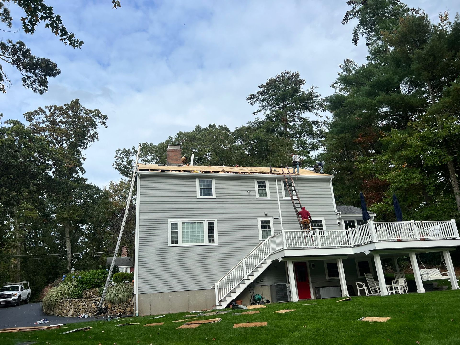 A man on a ladder is working on the roof of a house