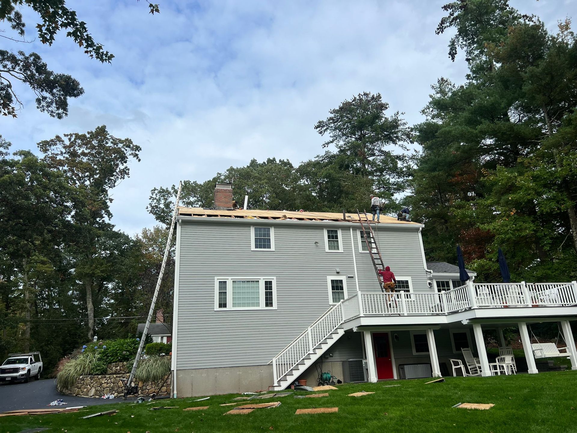 A man on a ladder is working on the roof of a house