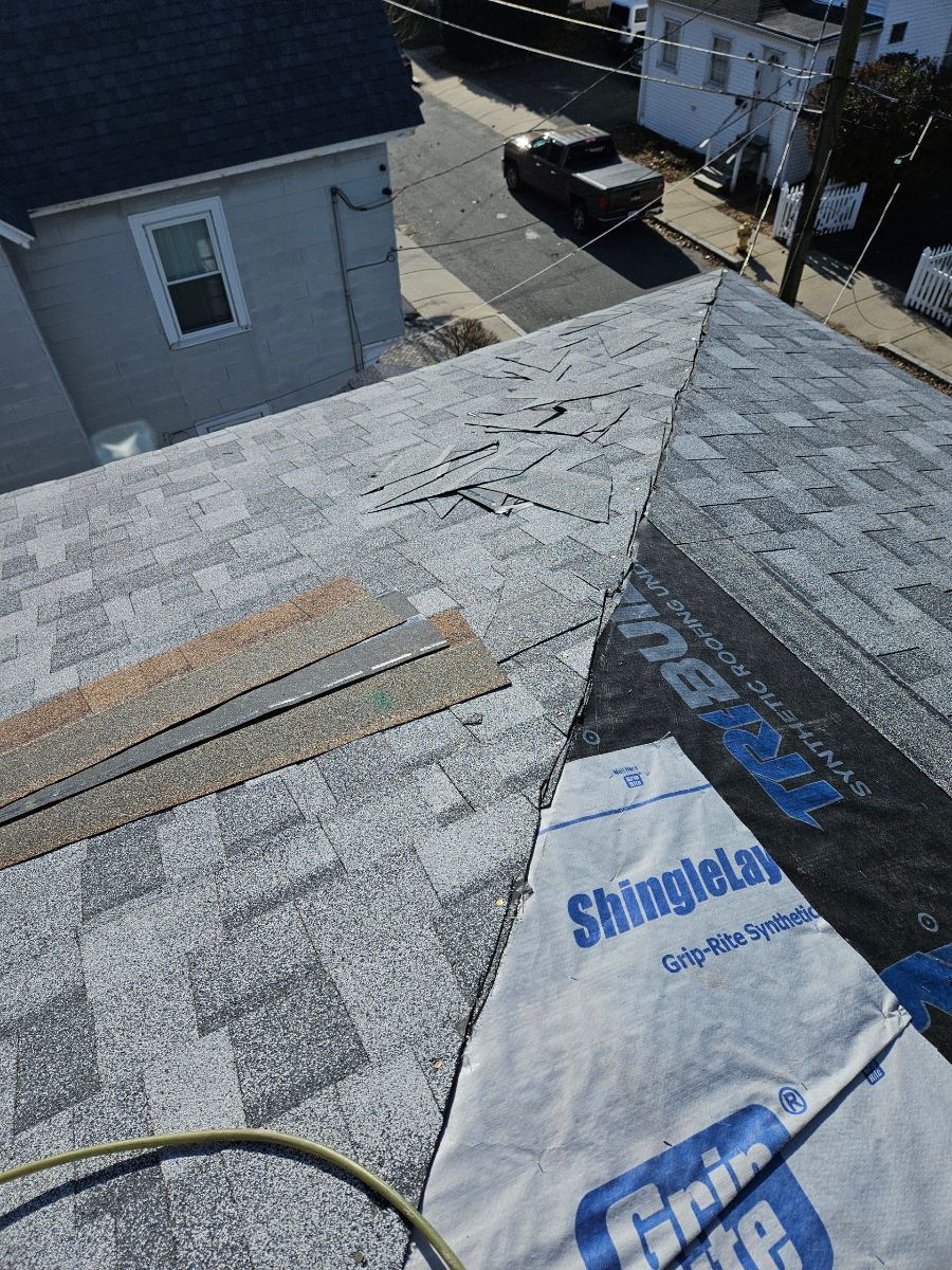 A roof with shingles being installed and a bag of shingles on it.