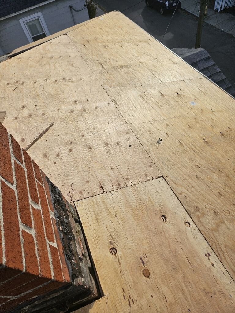 A brick chimney is sitting on top of a wooden roof.
