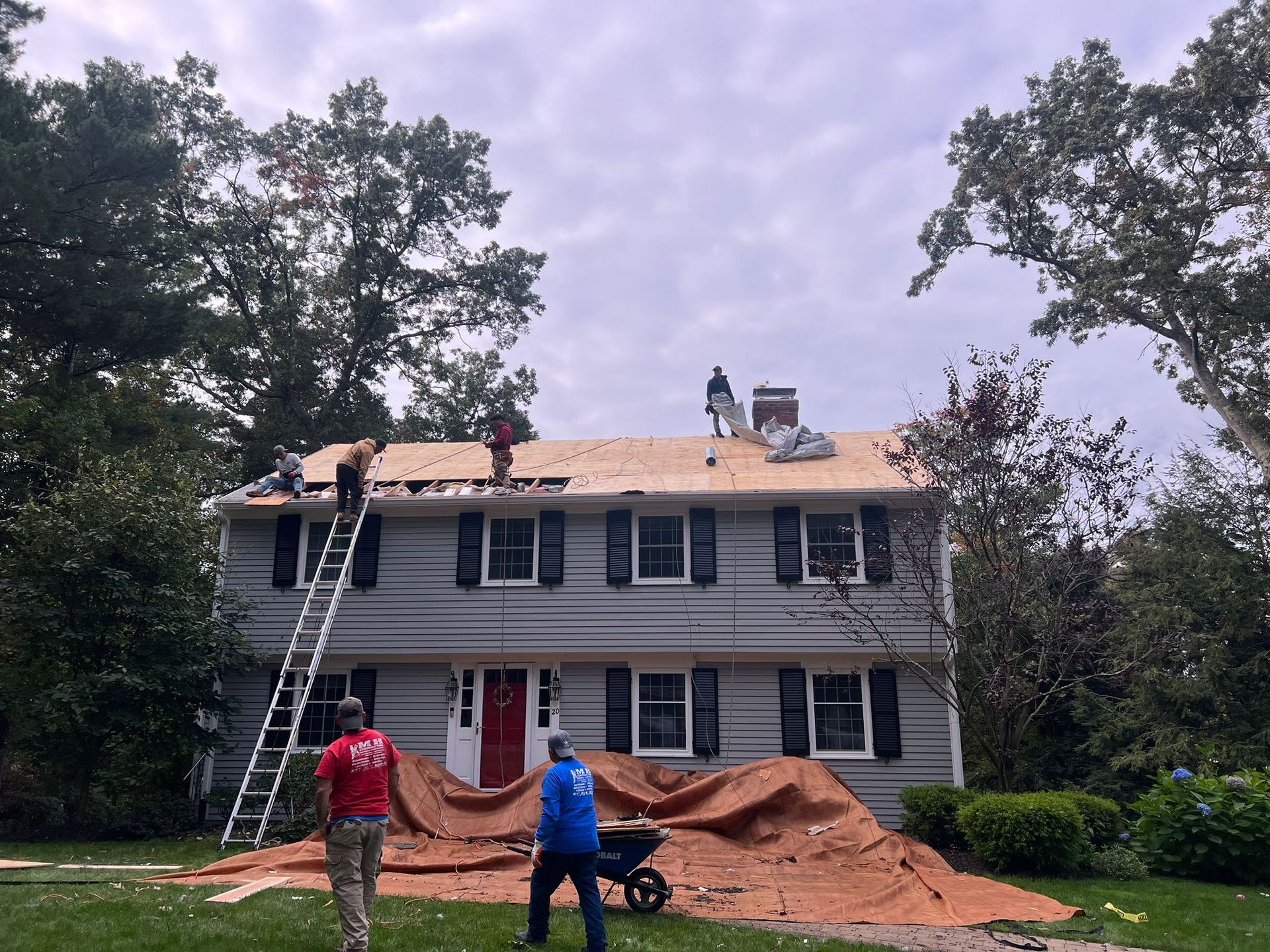 A group of people are working on the roof of a house.