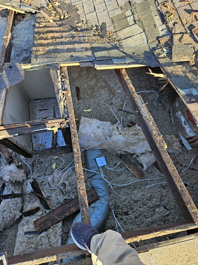 A person is standing on top of a roof that is being remodeled.