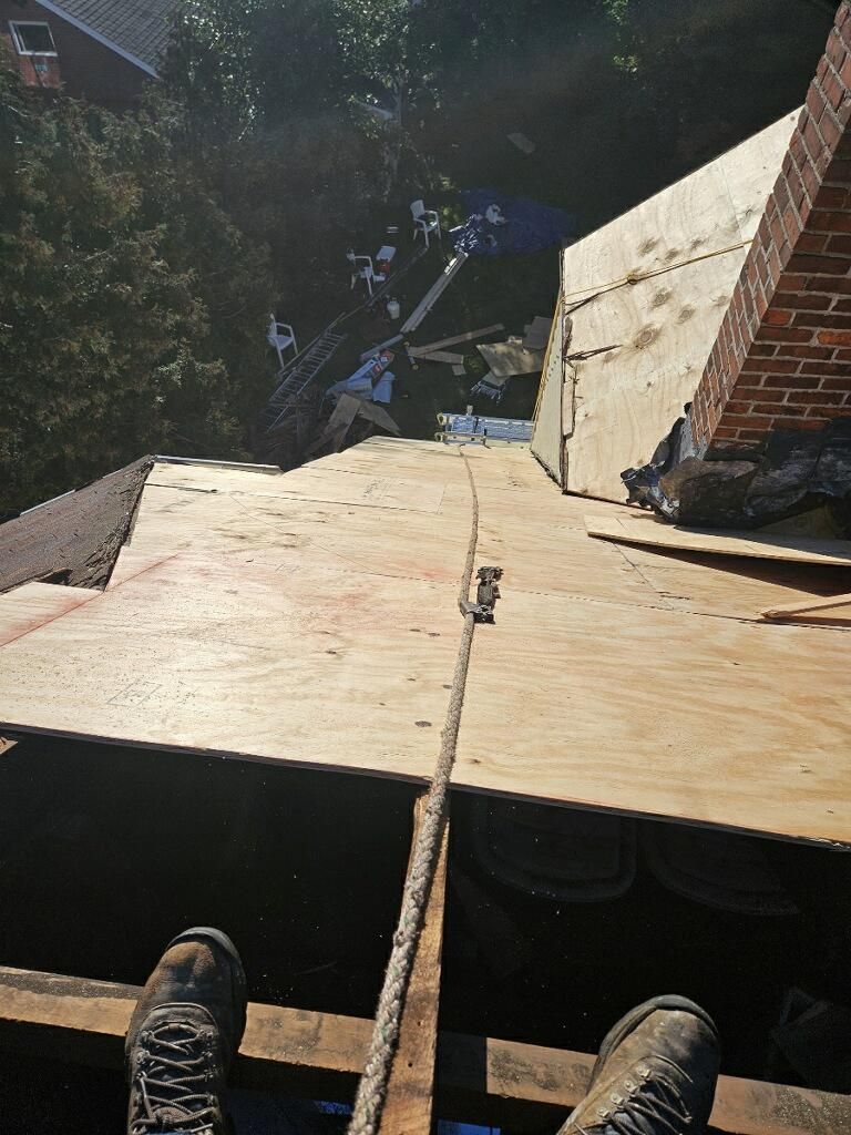 A person is standing on top of a wooden roof.