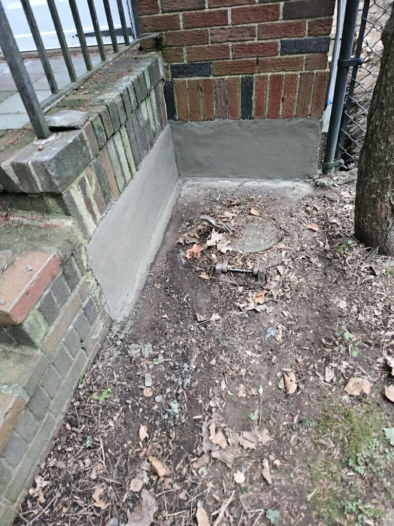 A brick building with a concrete walkway next to it.