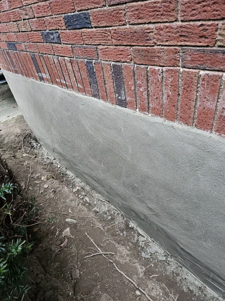 A close up of a brick wall with a concrete foundation.
