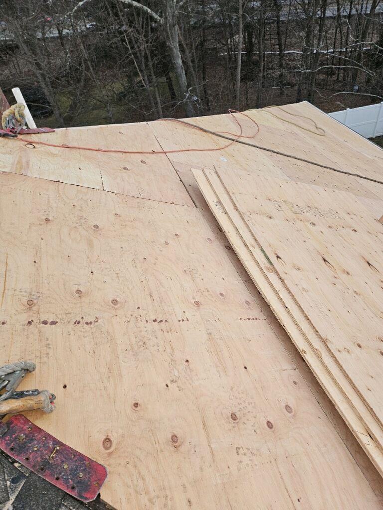 A person is cutting a piece of plywood on a roof.