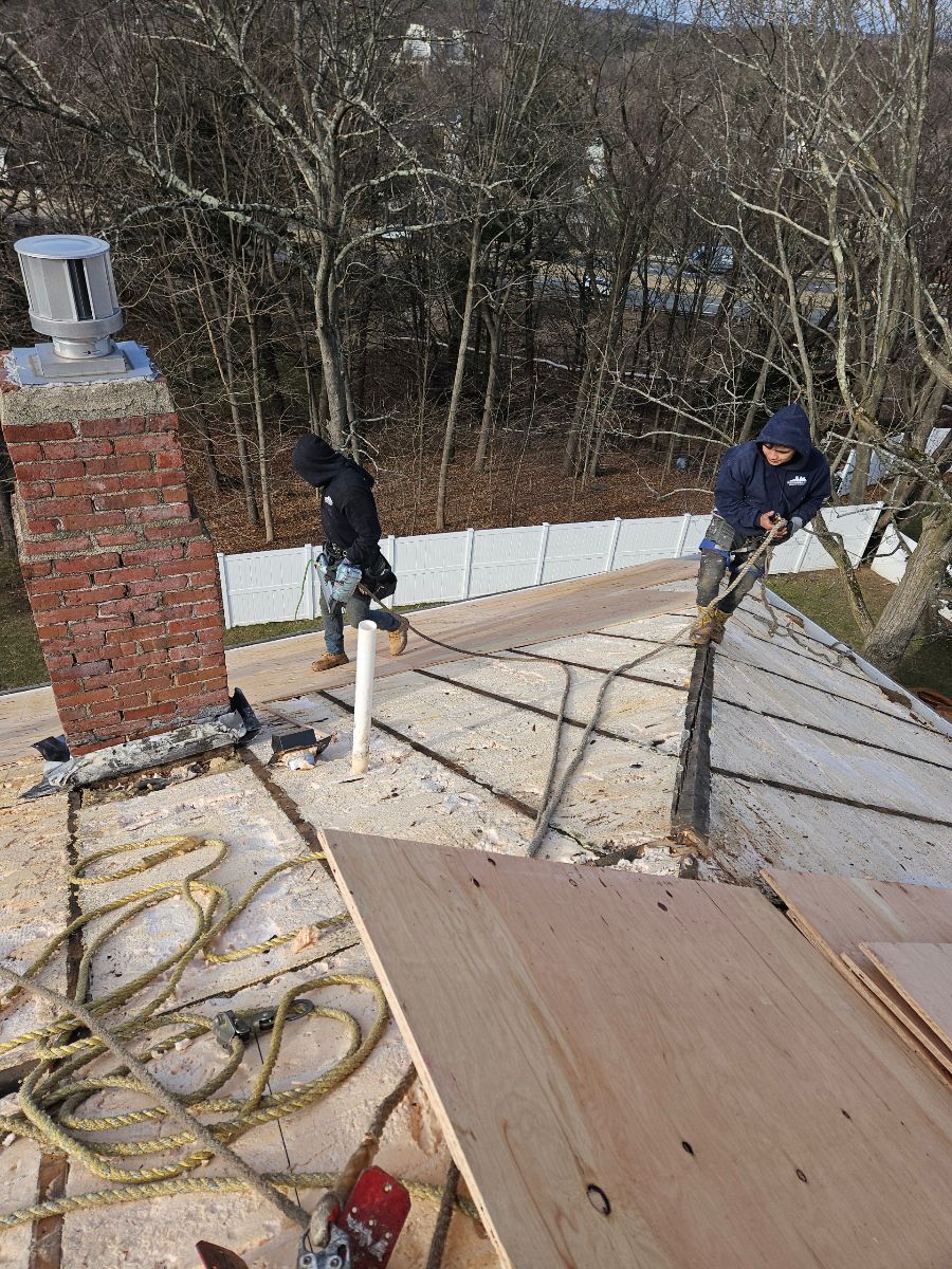 Two men are working on the roof of a house.