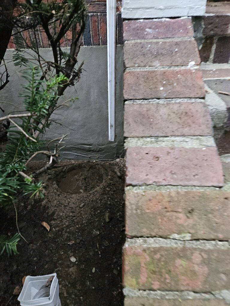 A brick wall is being built next to a concrete walkway.