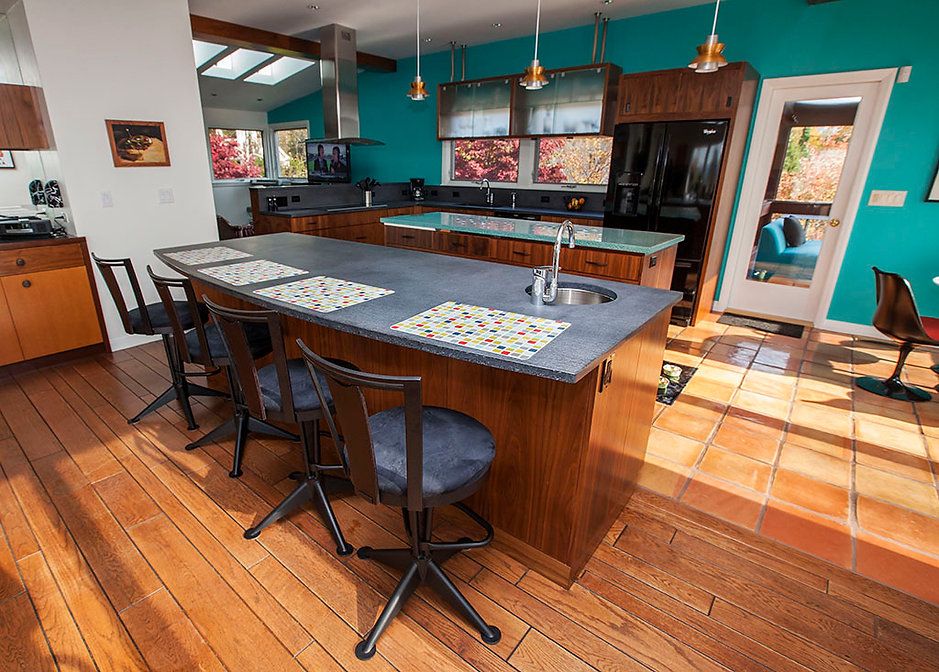 Kitchen with island and stools, turquoise walls, wood floor, stainless steel appliances.
