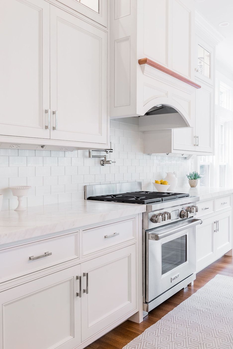 White kitchen with stove, cabinets, and tile backsplash; wooden accents.