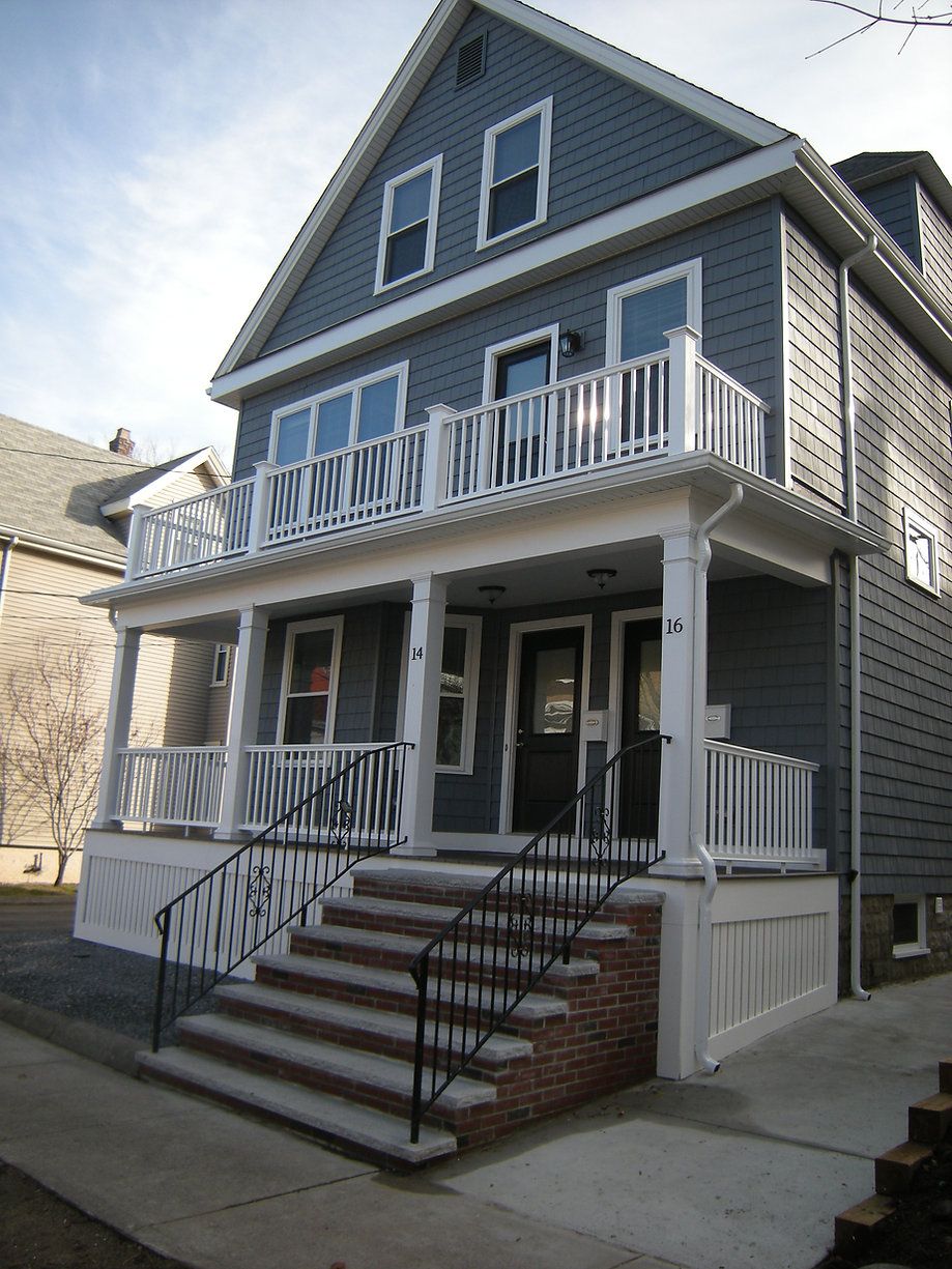 Two-story gray house with white trim, front porch, and stairs.