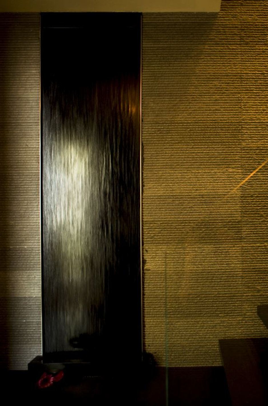 Vertical dark wood panel between two textured beige walls.
