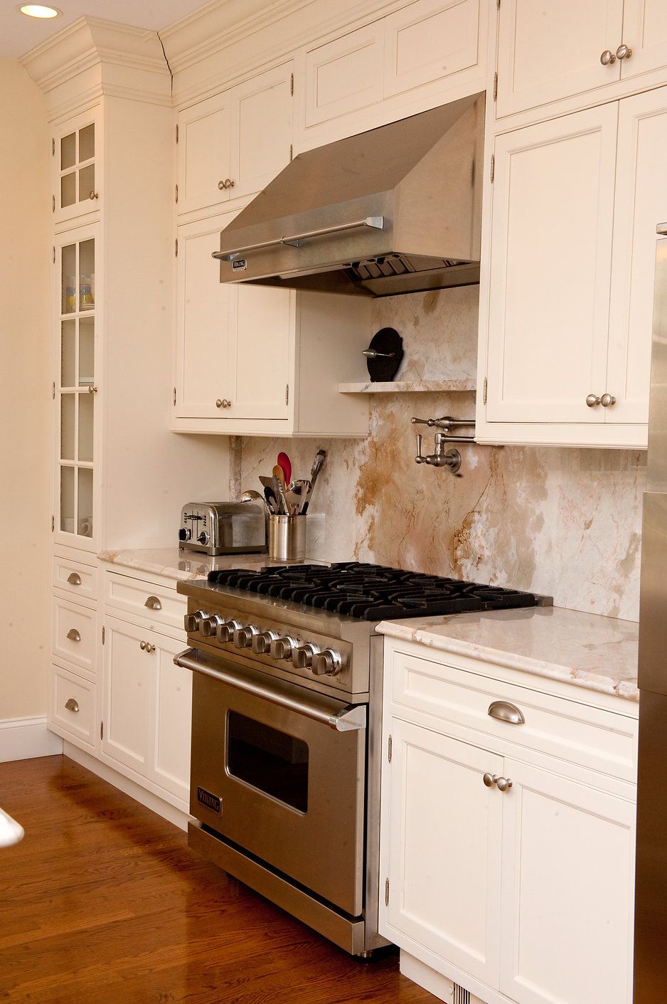 Kitchen with white cabinets, stainless steel range, range hood, and backsplash.
