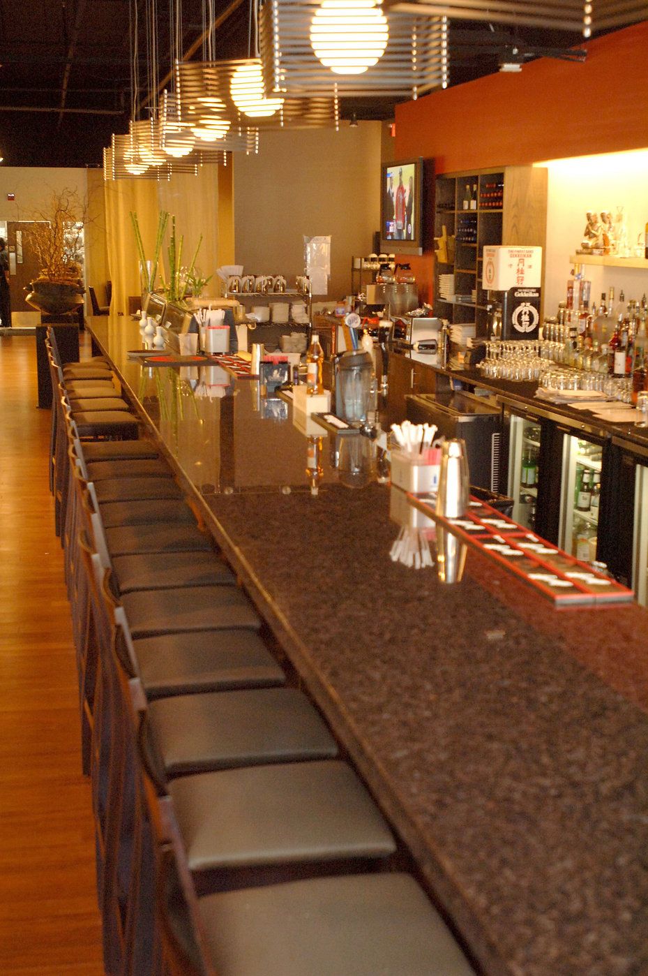 Long bar with leather stools, granite counter, and overhead lights in a restaurant.