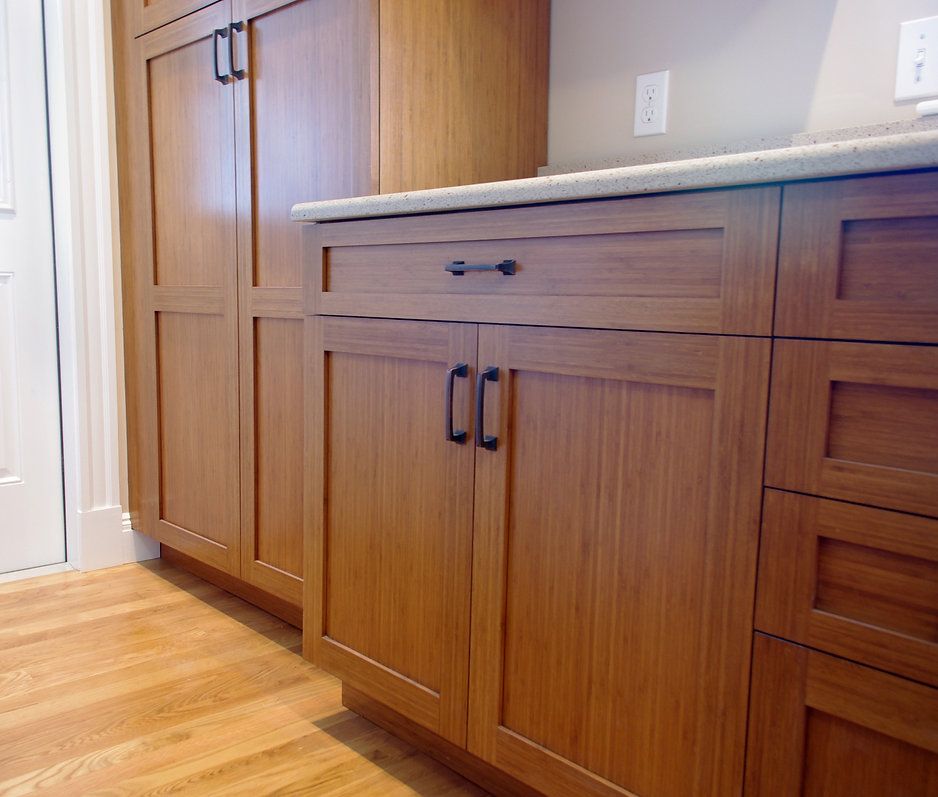 Wooden kitchen cabinets with black handles and a light countertop.