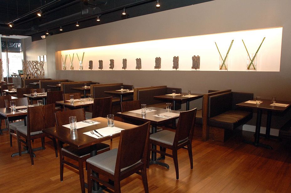 Restaurant interior with tables, chairs, and a decorative wall niche. Wooden floors, neutral walls.