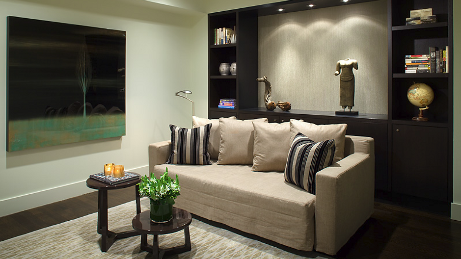 Cozy living room with beige sofa, dark built-ins, and abstract painting.