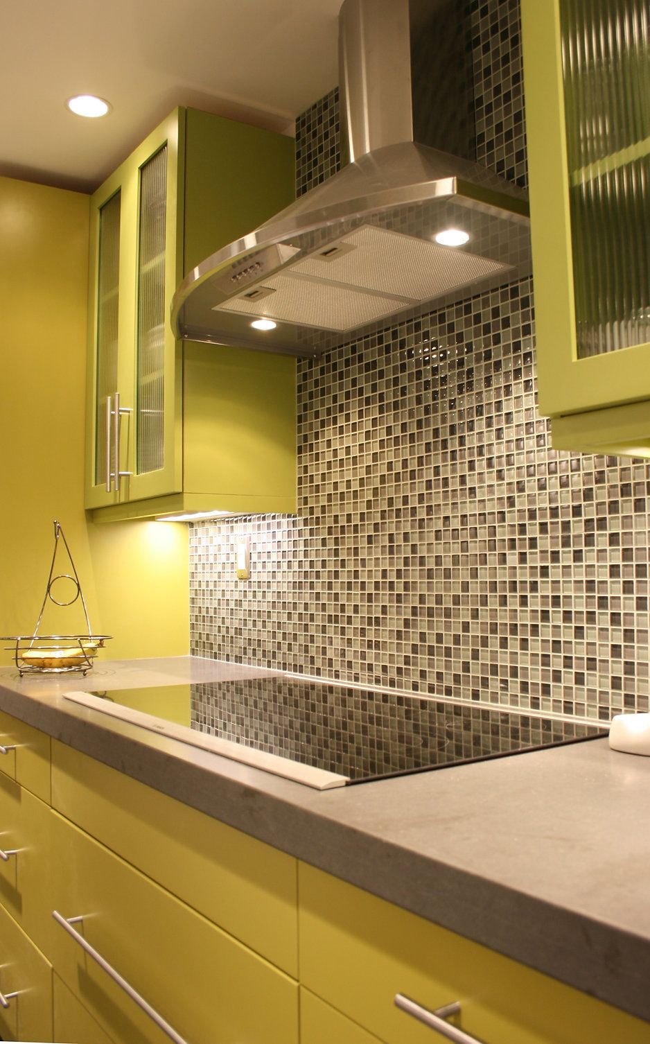 Lime green kitchen with gray countertop, stainless steel hood, and mosaic backsplash.