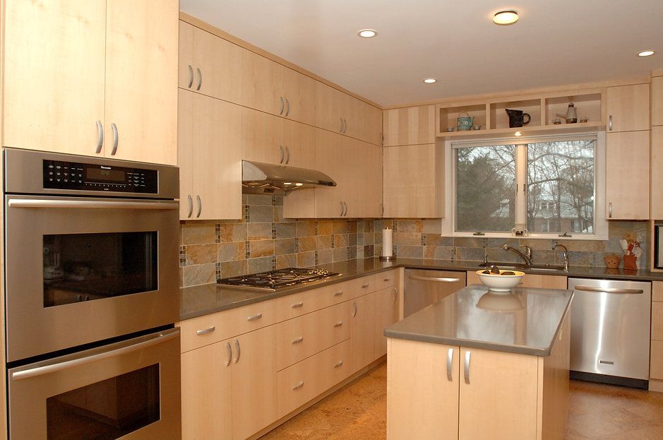 Modern kitchen with light wood cabinets, stainless steel appliances, and a center island.
