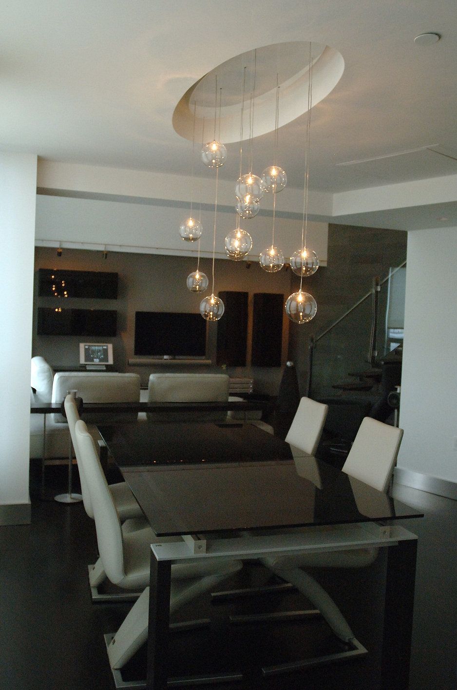Dining room with a modern table and chairs, lit by hanging globe lights.