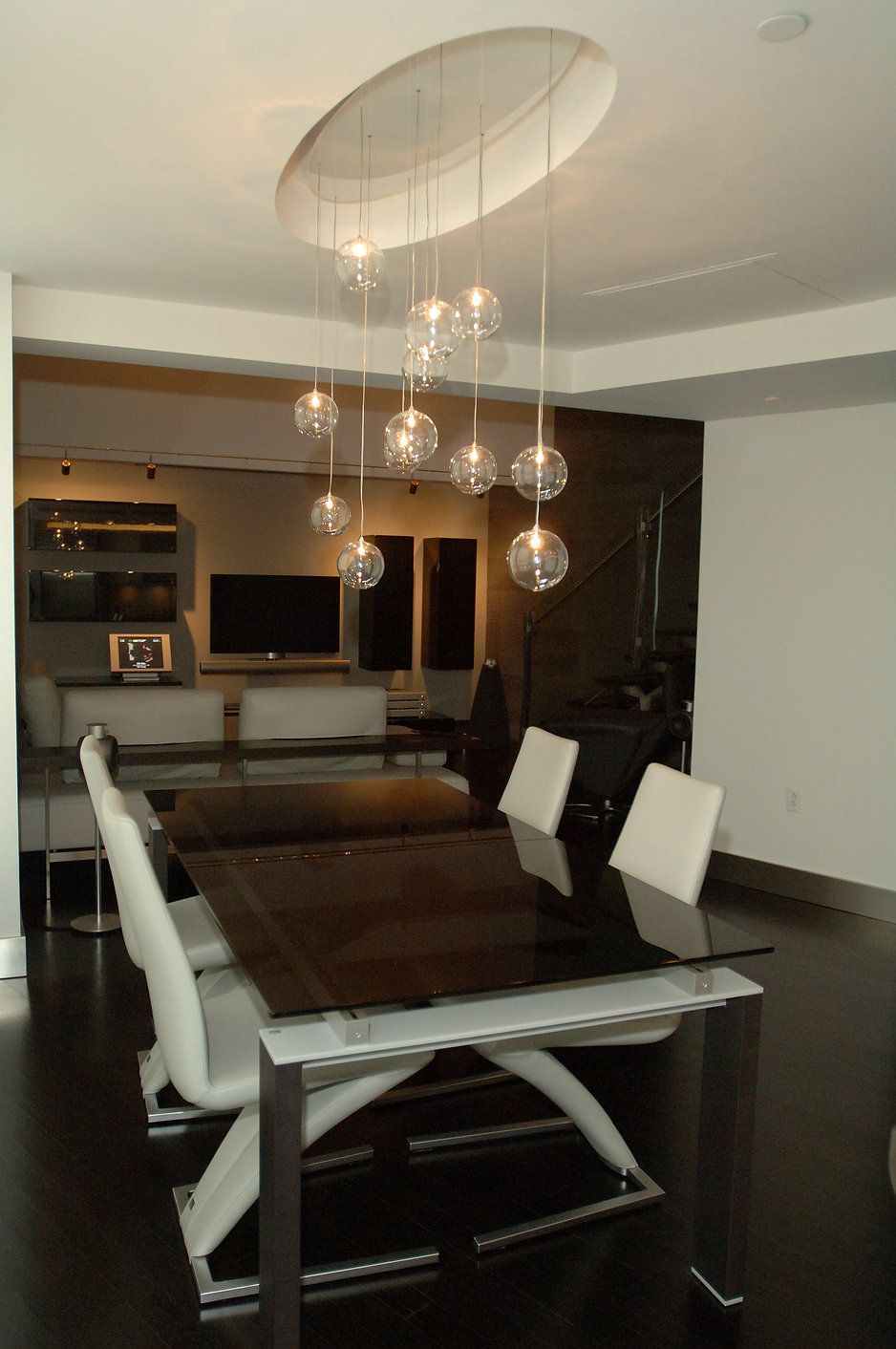 Modern dining room with black table, white chairs, and orb pendant lights.