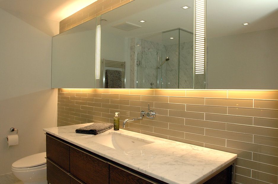 Bathroom with a large mirror, modern sink, tiled wall, and toilet.