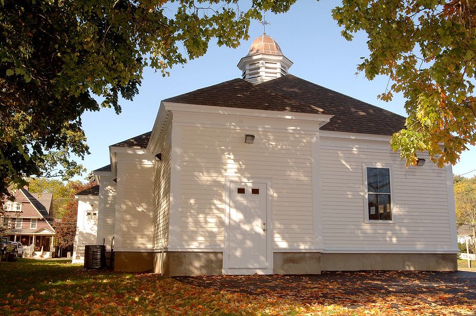 White, octagonal church with a cupola, autumn leaves in foreground.