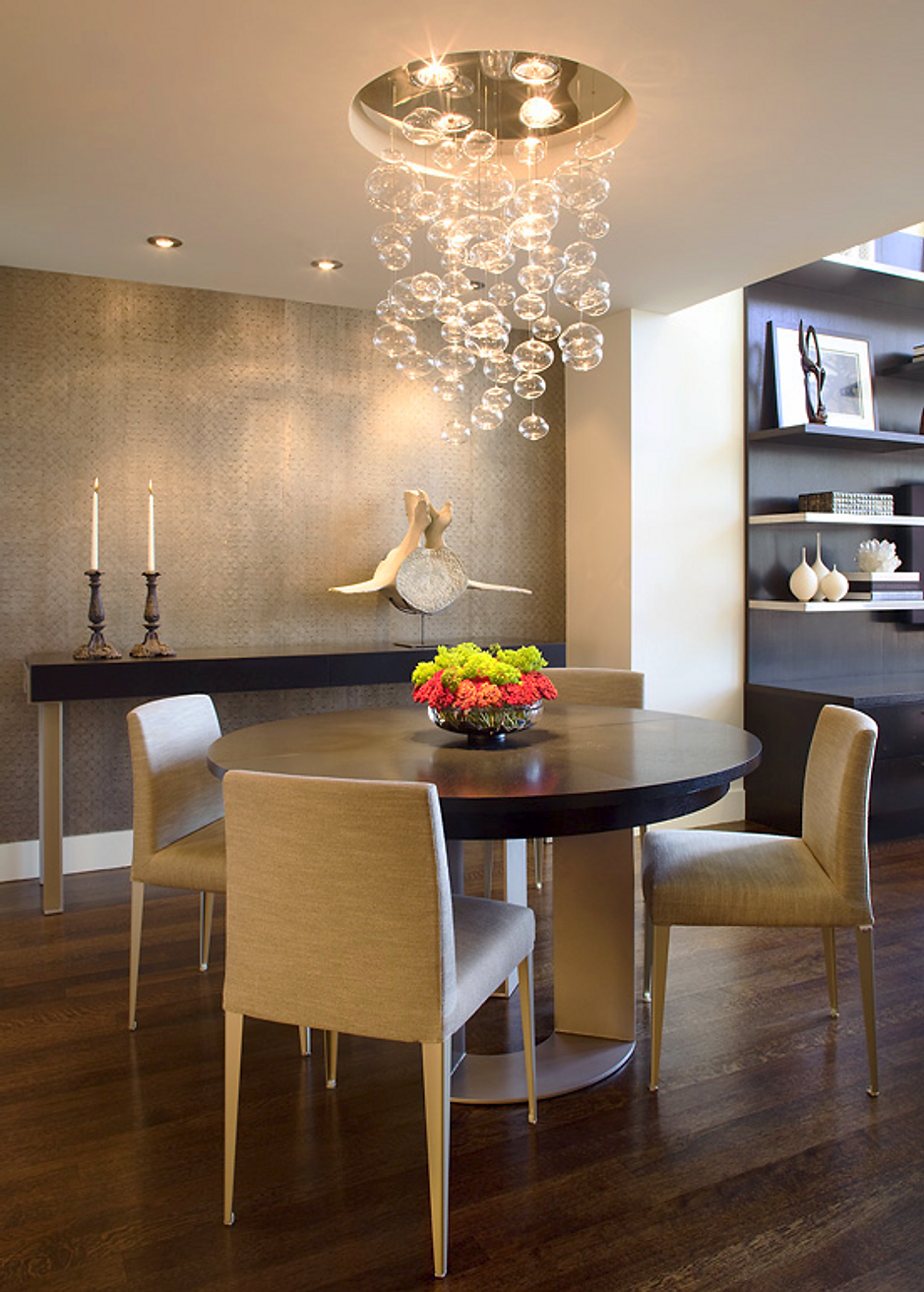 Dining room with a round table, chairs, and a bubble chandelier. Gold and dark wood accents.