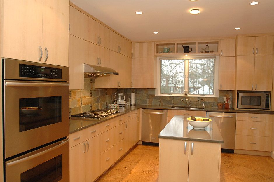 Modern kitchen with light wood cabinets, stainless steel appliances, and island.