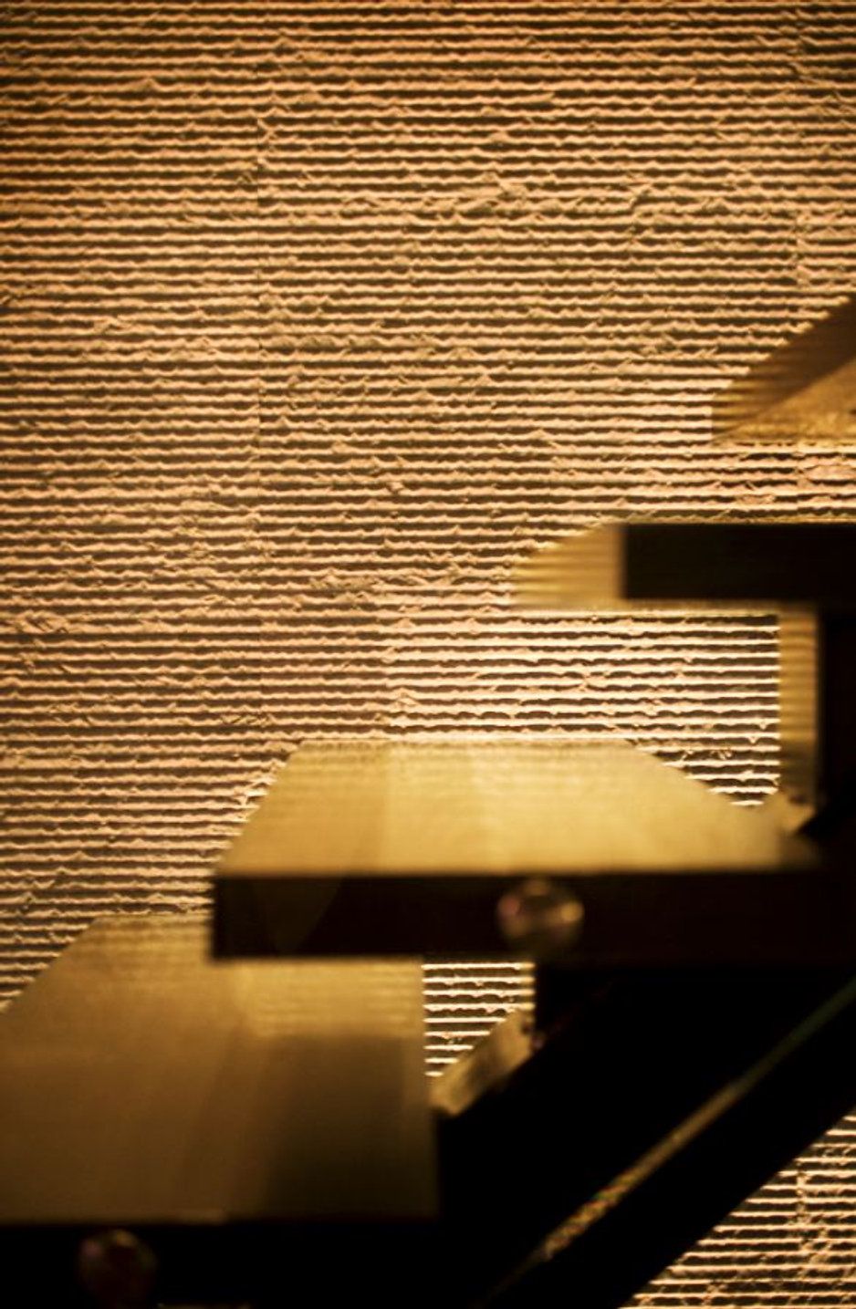 Wooden staircase against textured, golden-toned wall.
