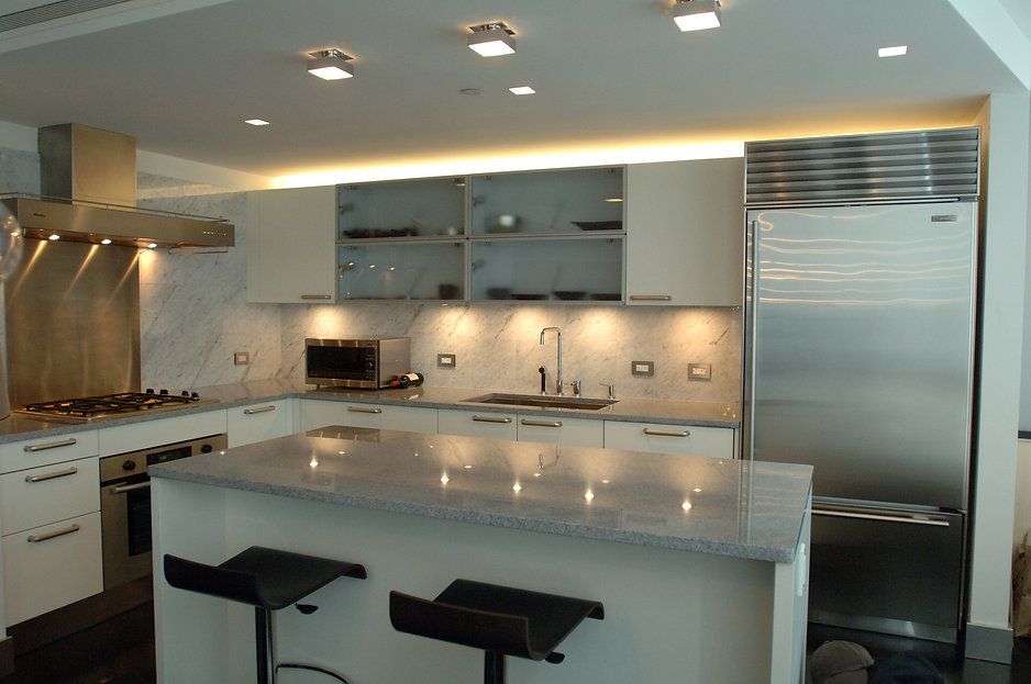 Modern kitchen with stainless steel appliances, white cabinets, and granite island with bar stools.