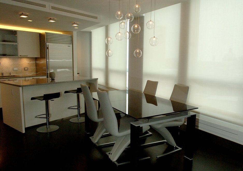 Modern kitchen with dining area; white and black decor, large windows, pendant lights.