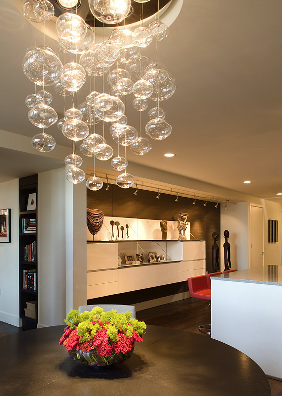Modern dining room with bubble chandelier over a dark table with a flower arrangement.