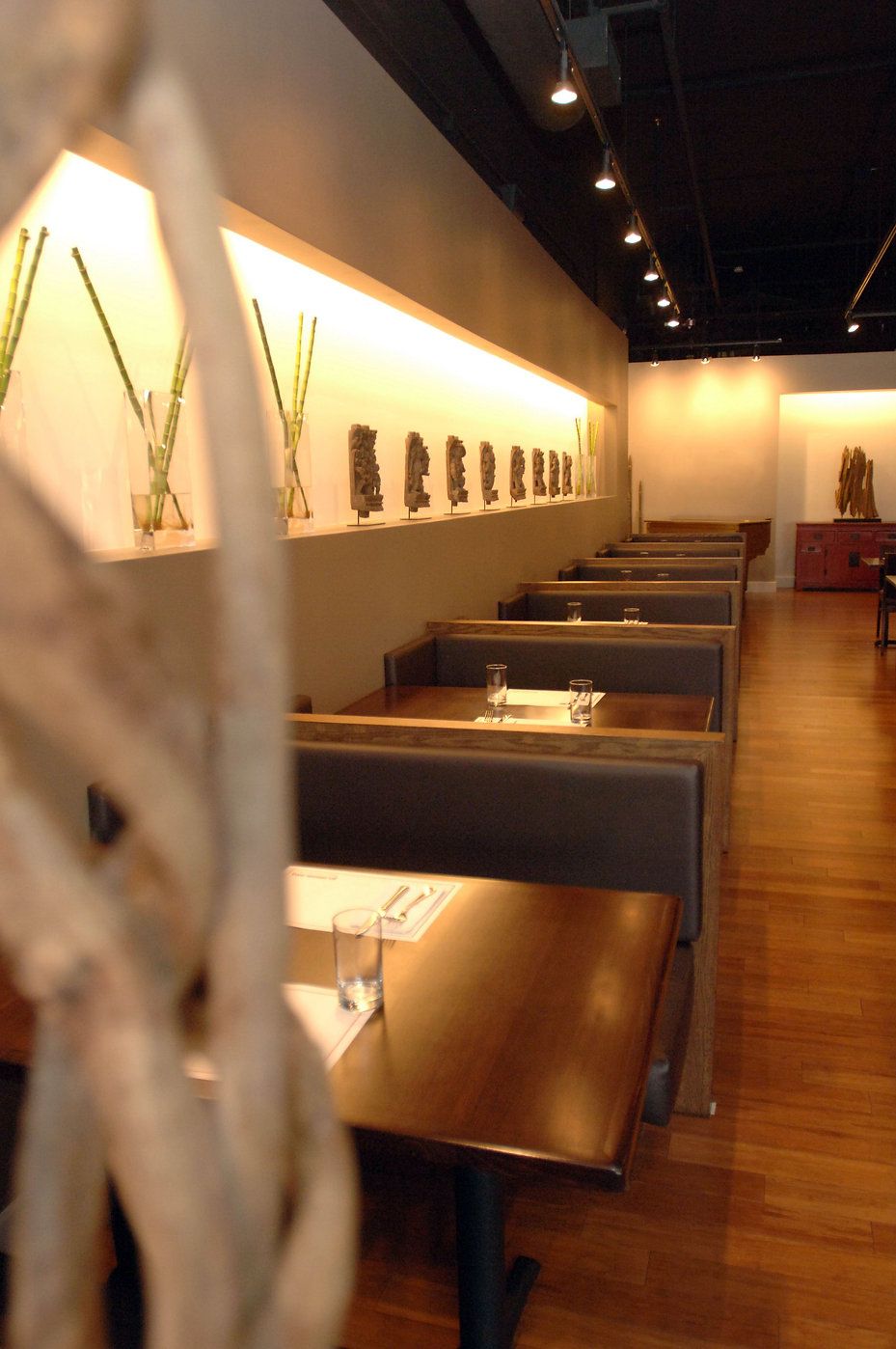 Empty restaurant with booths, wooden tables, art on the wall, and hardwood floors.