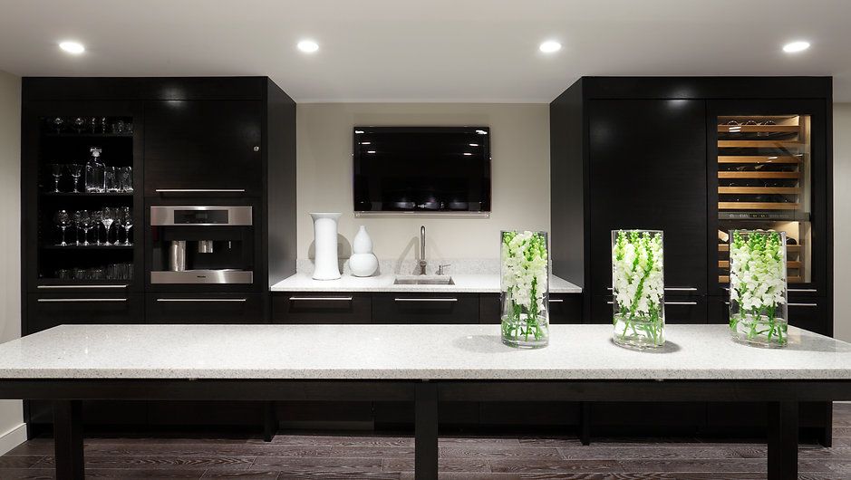 Modern dark kitchen with island, cabinets, appliances, and decorative vases.