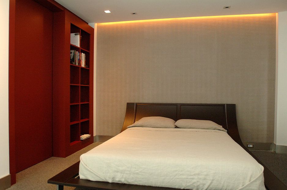 Bedroom with a bed, reddish-brown closet/shelving, and neutral-colored walls and bedding.