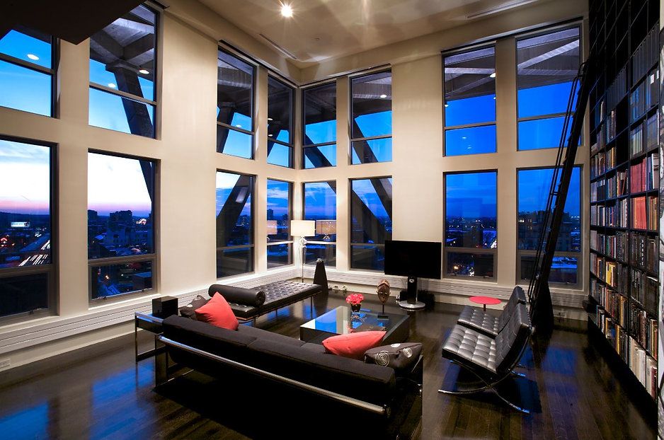 Modern living room with large windows, dark furniture, and city views.
