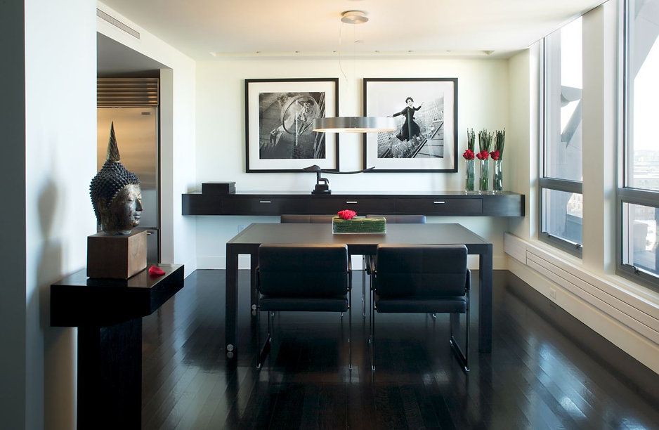 Modern dining room with black table and chairs, artwork, and Buddha statue.