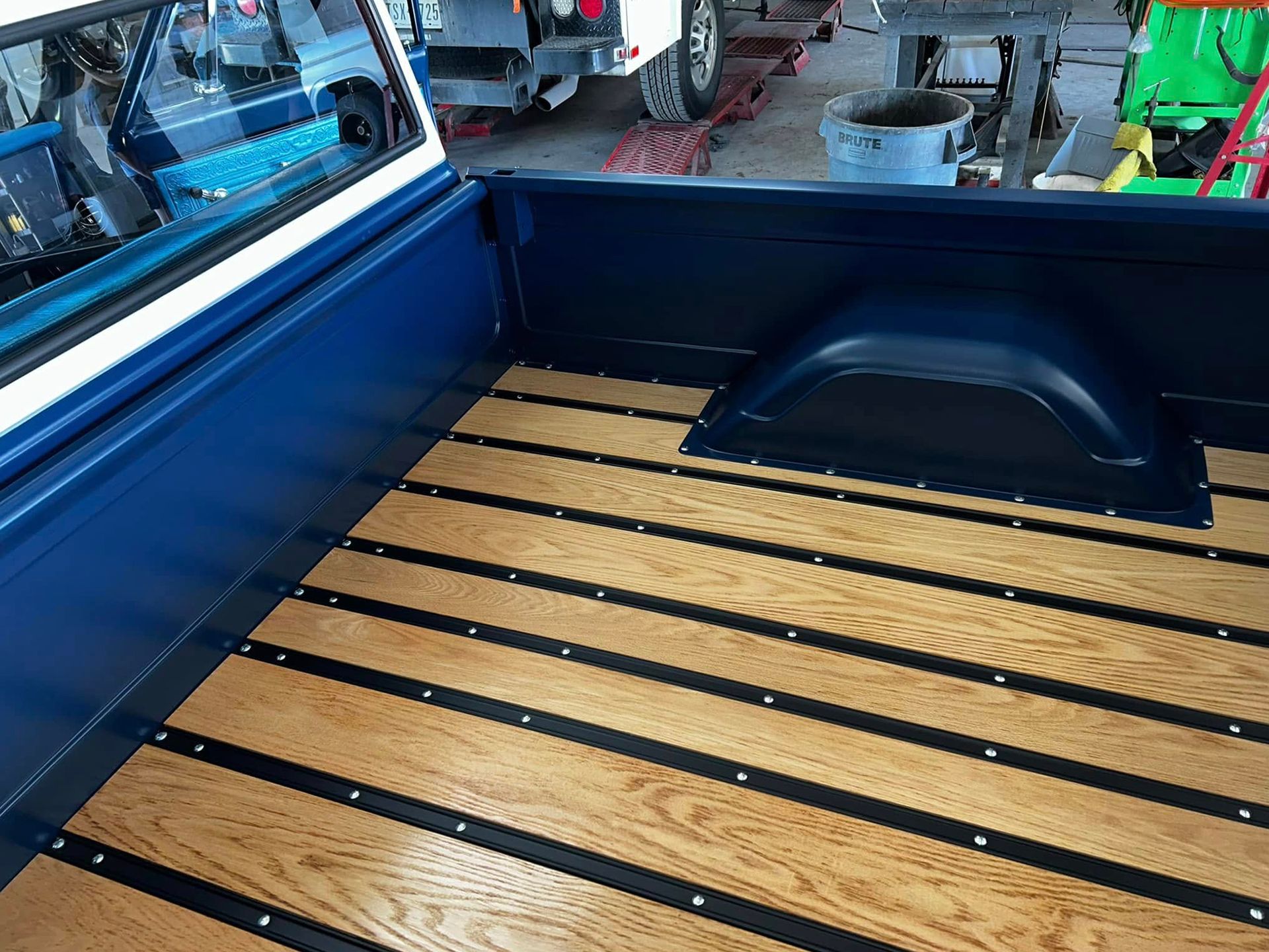Blue truck bed with wooden slats and dark metal strips.