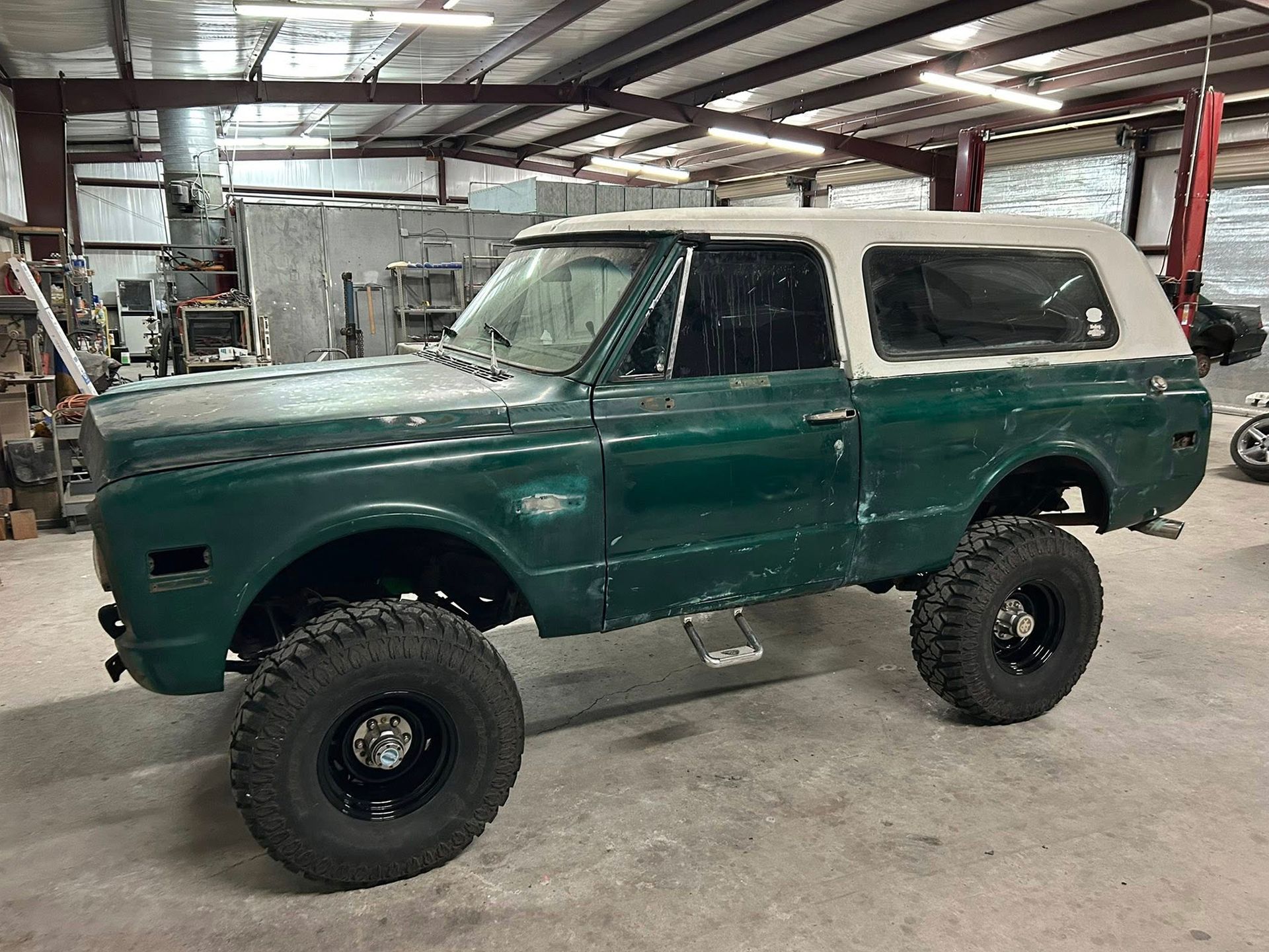 Green lifted vintage Chevy Blazer with a white top.