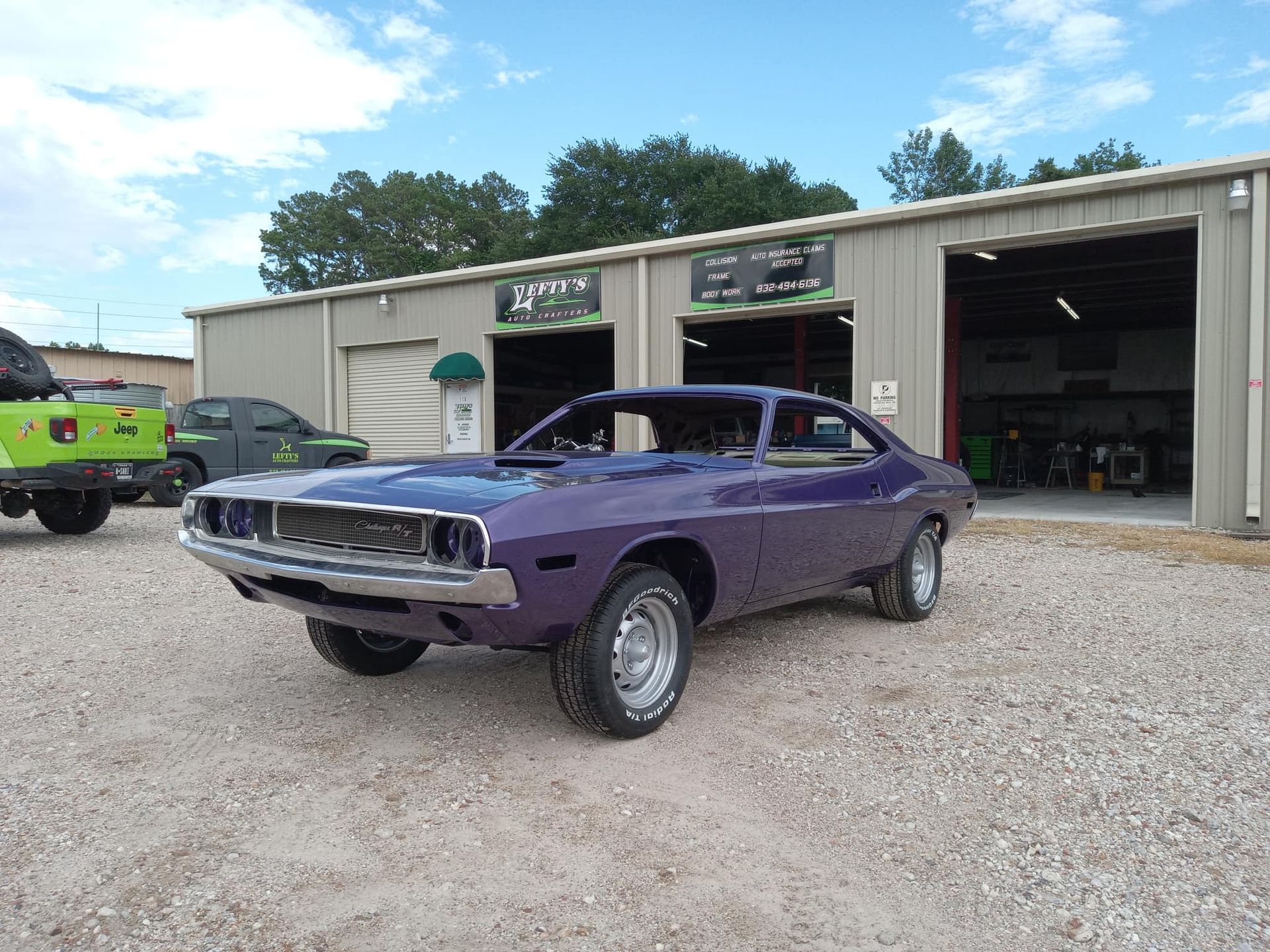 Purple classic car parked outside a garage.