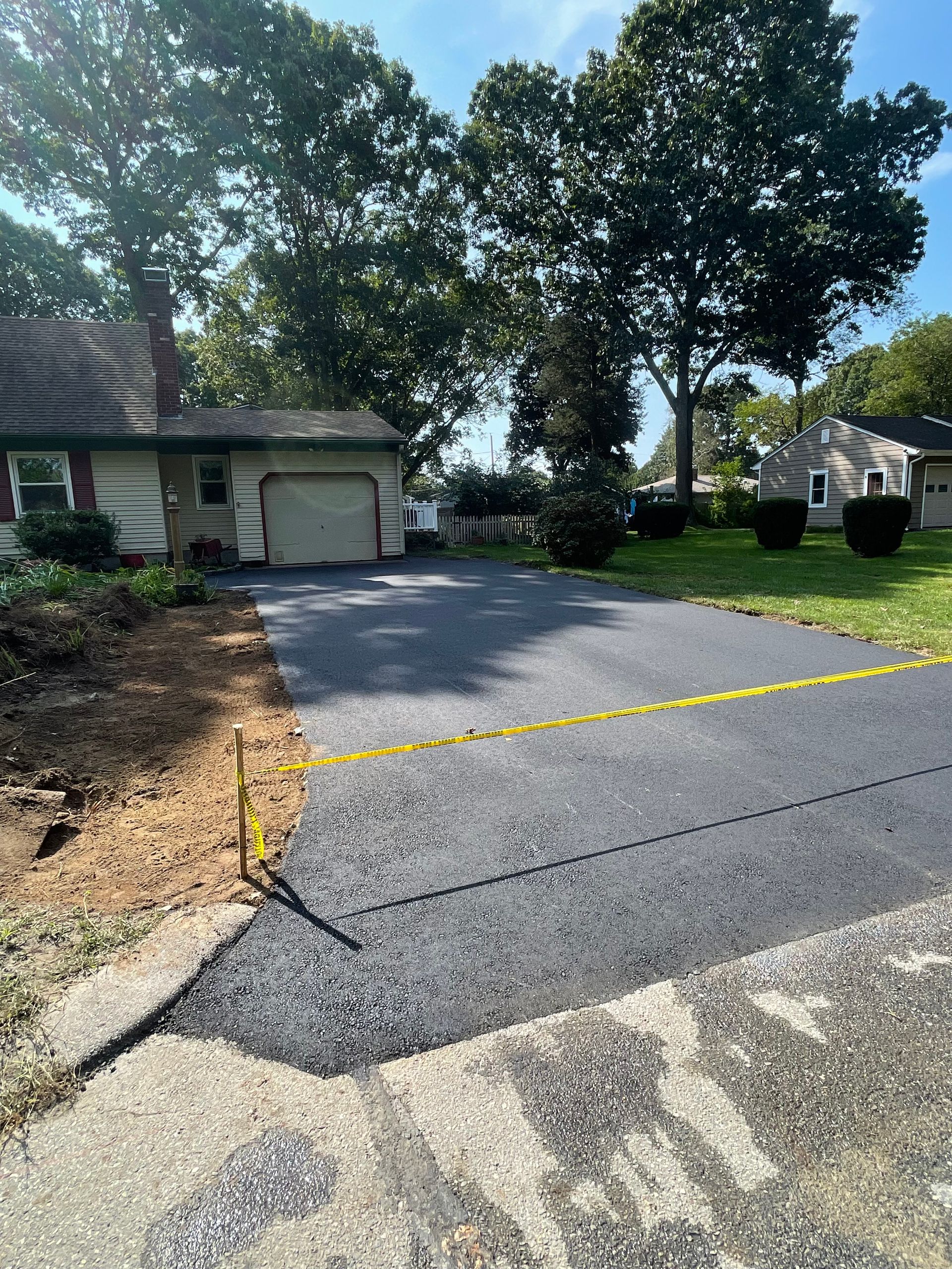 A driveway leading to a house with a garage and trees in the background.