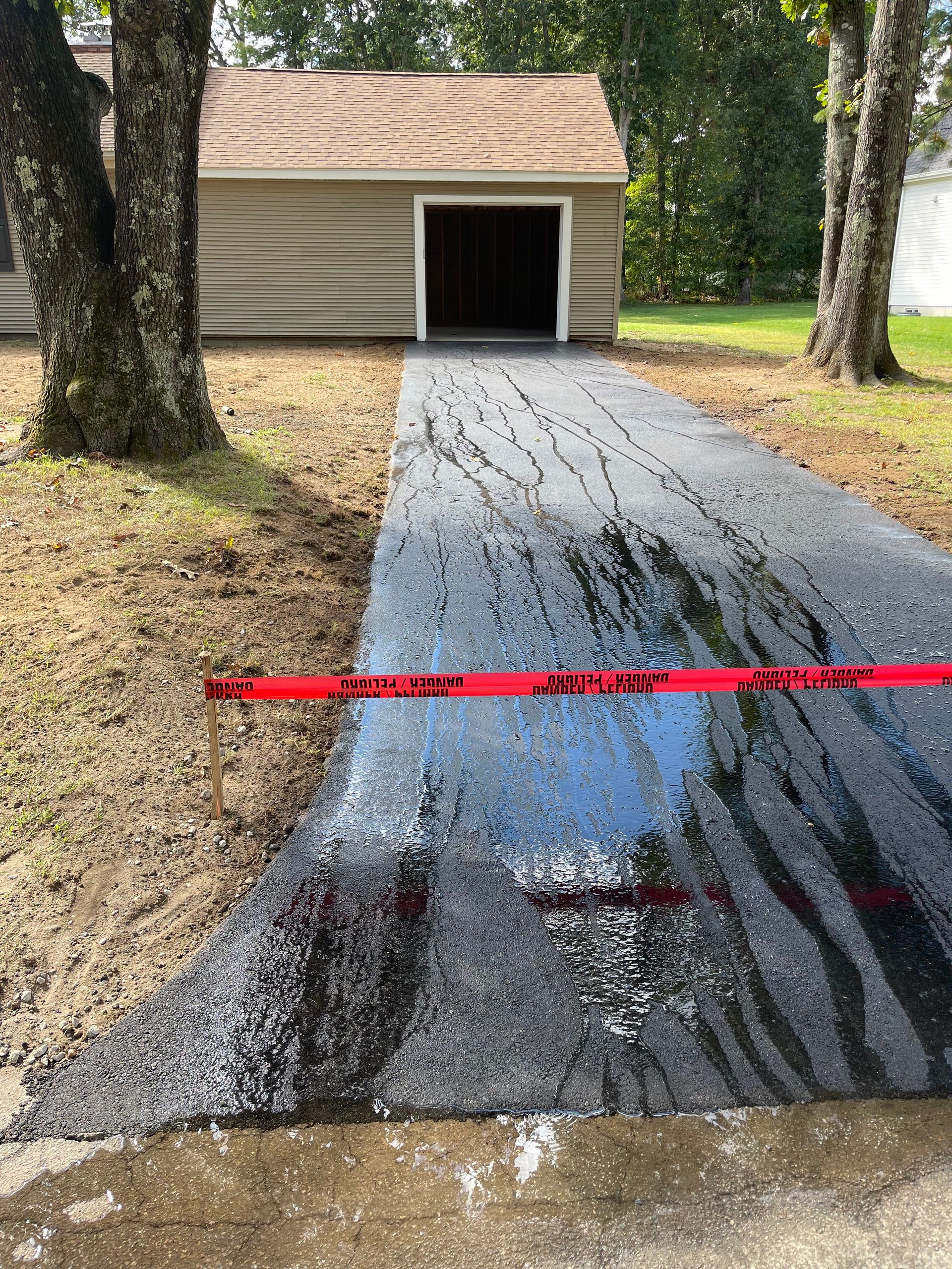 A driveway with a garage in the background and trees in the foreground.