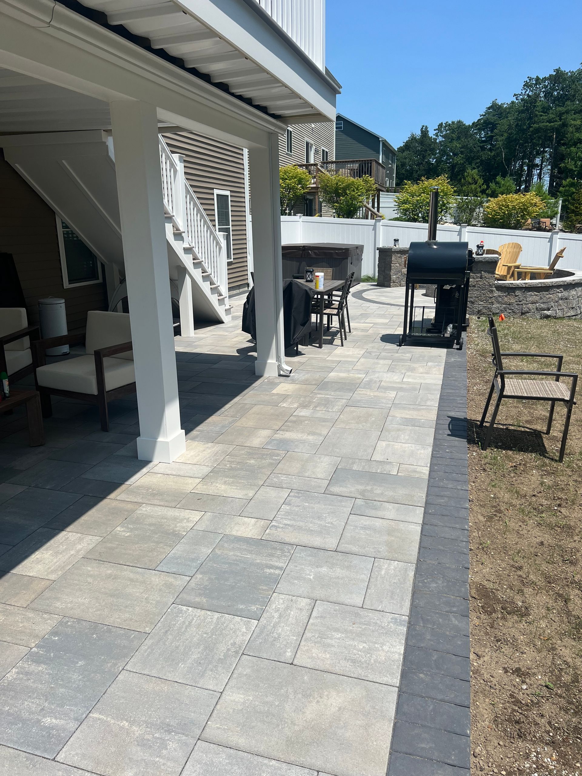A patio with a grill and chairs under a covered area